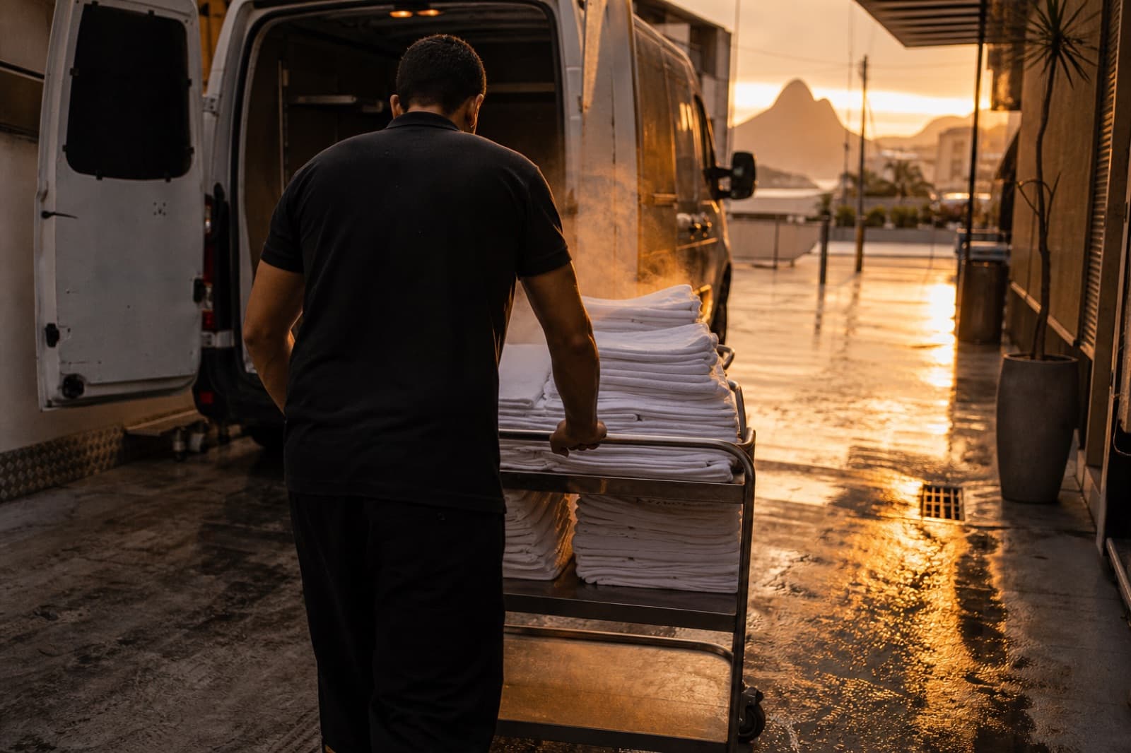 Entrega de enxoval limpo ao amanhecer: carrinho de toalhas saindo da van